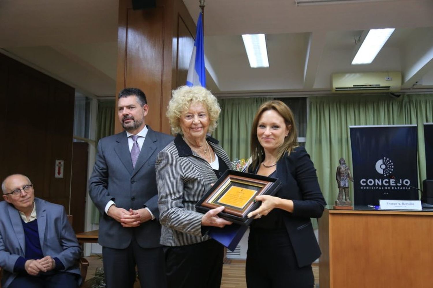 Brenda Vimo, autora del proyecto que distingue a Toti Tieri le entrega la plaqueta recordatoria