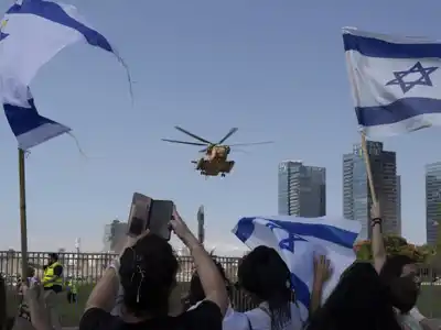 Personas festejan mientras el helicóptero que transporta a los rehenes liberados llega a un hospital, en Petah Tikva, Israel.