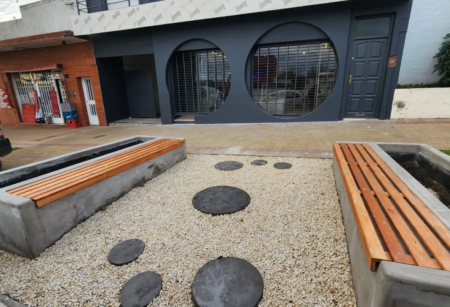 Un comerciante transformó un sector verde frente a su negocio con bancos, canteros y piedras decorativas.