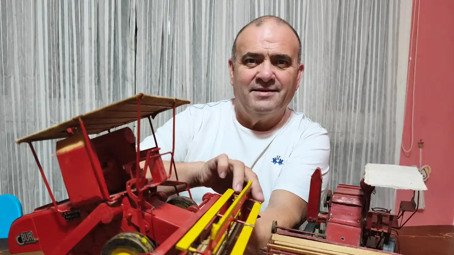 José María Barralle Barralle muestra dos maquetas, verdaderas reliquias de la maquinaria agrícola, fabricadas y donadas por Tadeo Buratovich.