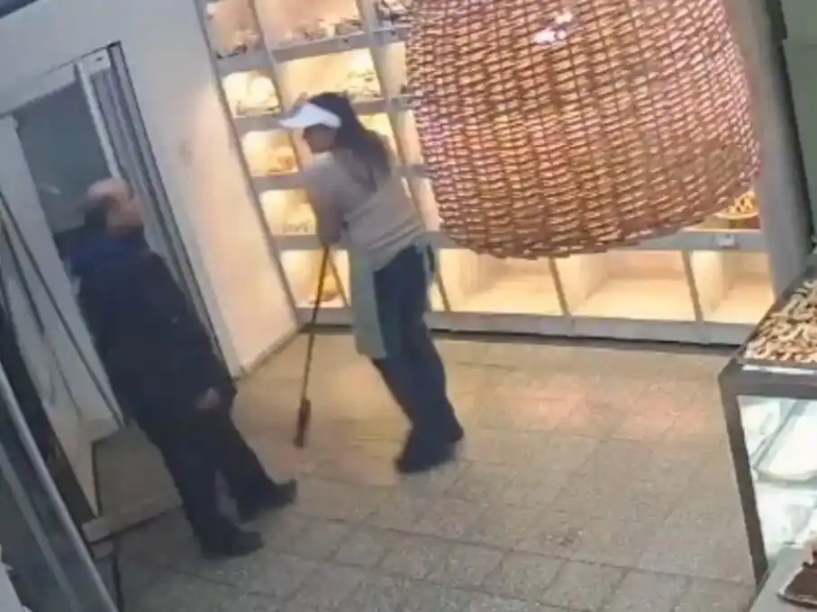 El momento en que el delincuente amenaza a la empleada de la panadería.