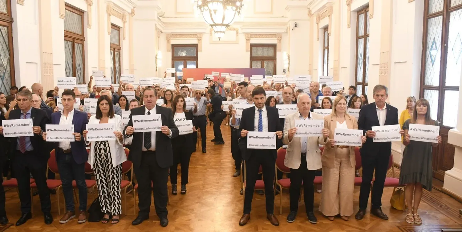 Autoridades y participantes del acto en el Salón Blanco con los carteles llamando a no olvidar y pidieron la liberación de los rehenes en manos de Hamas. Foto: Flavio Raina.