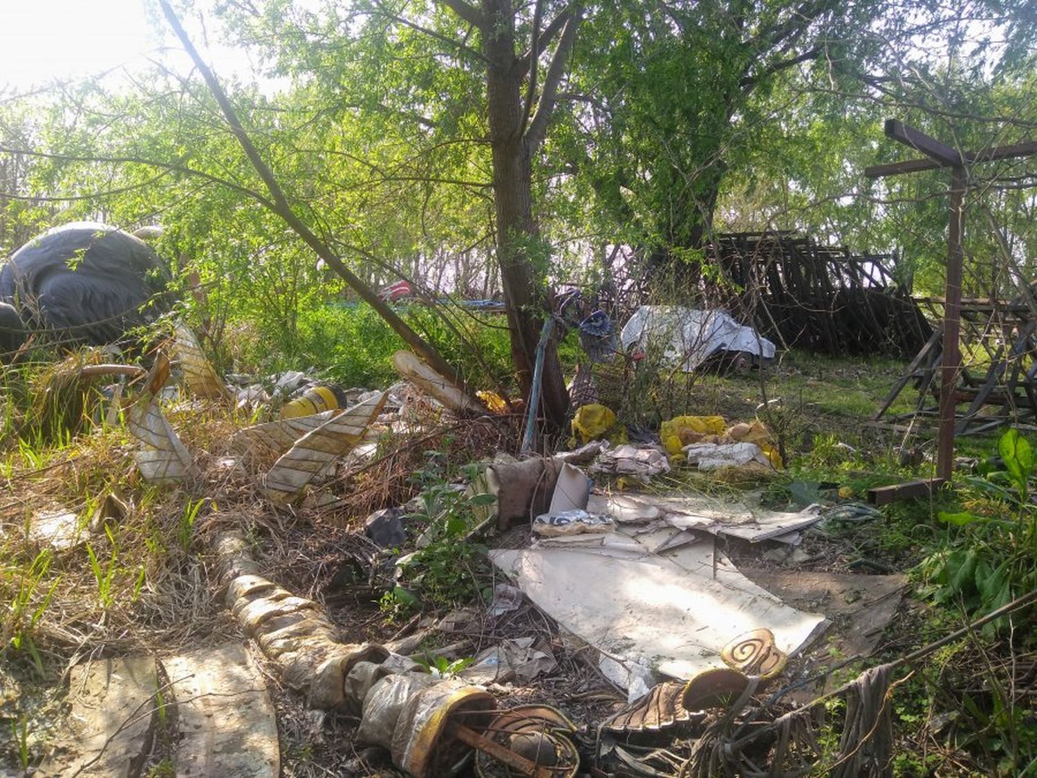 Basura dispersada en medio del monte, inclusive estructuras metálicas.