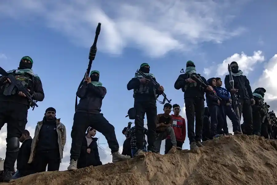 Civiles palestinos y milicianos de las brigadas de Izz ad-Din al-Qassam, brazo armado de Hamás, presenciaban la entrega de cuatro rehenes israelíes a la Cruz Roja en el sur de la Franja de Gaza.EFE