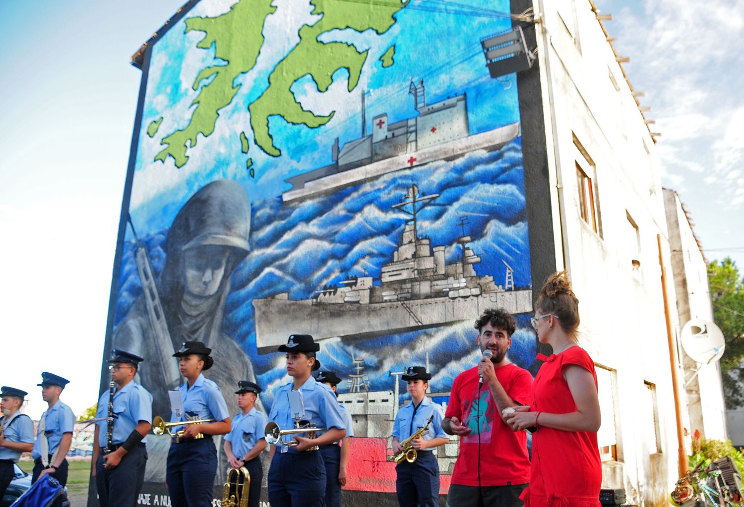 Los artistas, junto a la banda "Cuna de Héroes", y uno de los murales.