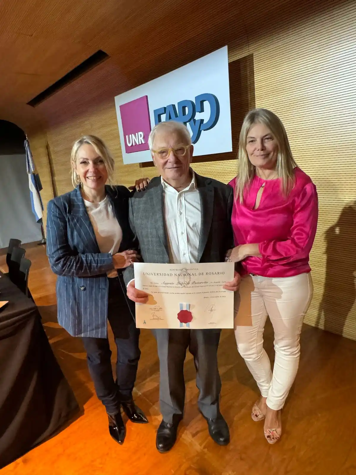 El arquitecto Augusto Pantarotto recibe la distinción de manos de autoridades de la UNR, durante el acto realizado en la FAPyD.