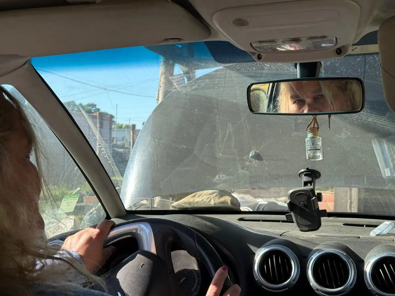 Moni, al volante de su auto, mientras parte de su familia repara el remis.