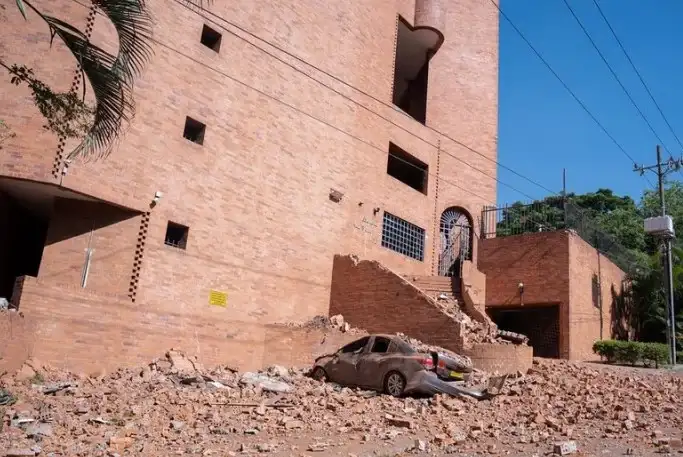 Un edificio dañado y un vehículo cubierto de escombros en Cali, Colombia.
