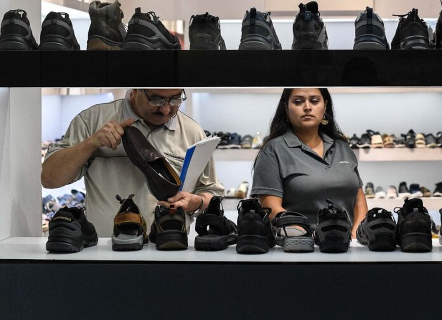 Personas observan zapatos en una tienda de calzado.