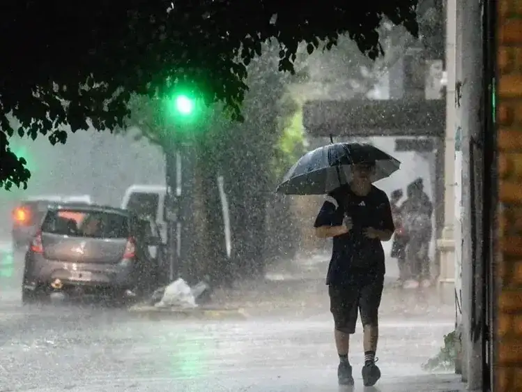 Un peatón camina bajo la intensa lluvia en las calles de Formosa, protegiéndose con un paraguas mientras el temporal afecta la visibilidad y el tránsito vehicular en la ciudad ante la alerta meteorológica vigente por fuertes vientos y granizo.