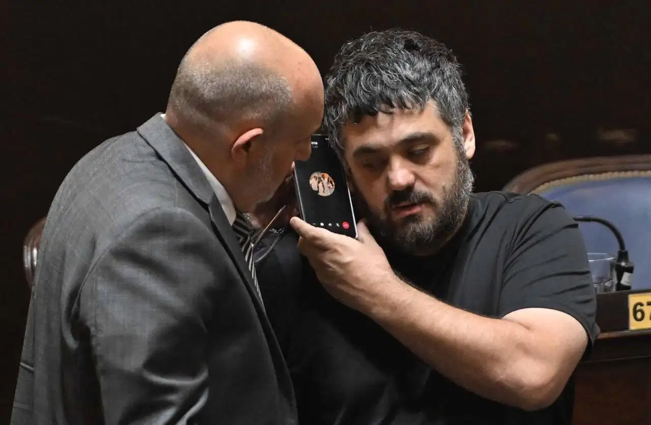 Facundo Tignanelli sostiene un teléfono con el contacto de Sergio Massa mientras conversa junto a Alexis Guerrera en el recinto de Diputados bonaerense durante la fallida sesión por el endeudamiento.