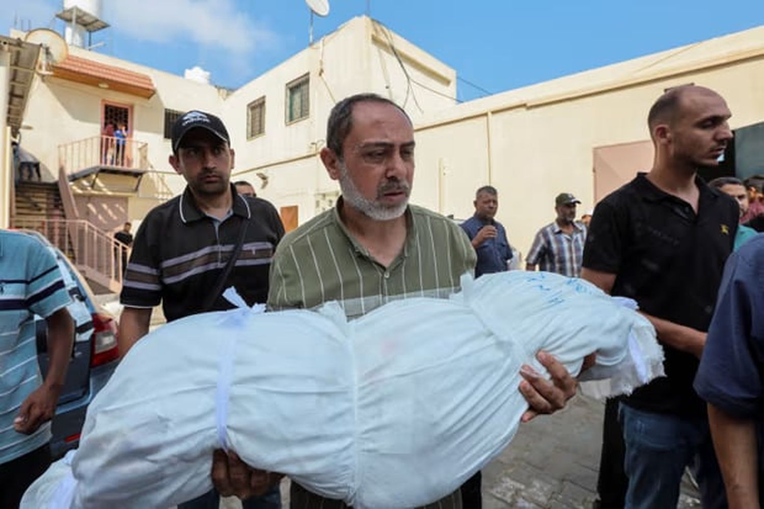 A mourner carries the body of a Palestinian child killed in an Israeli strike in Deir Al-Balah, Gaza