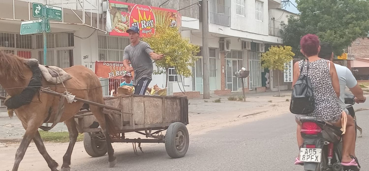 Motociclistas sin casco pasan al lado de un cartonera que conduce un carro de tracción a sangre en la Interbarrial.