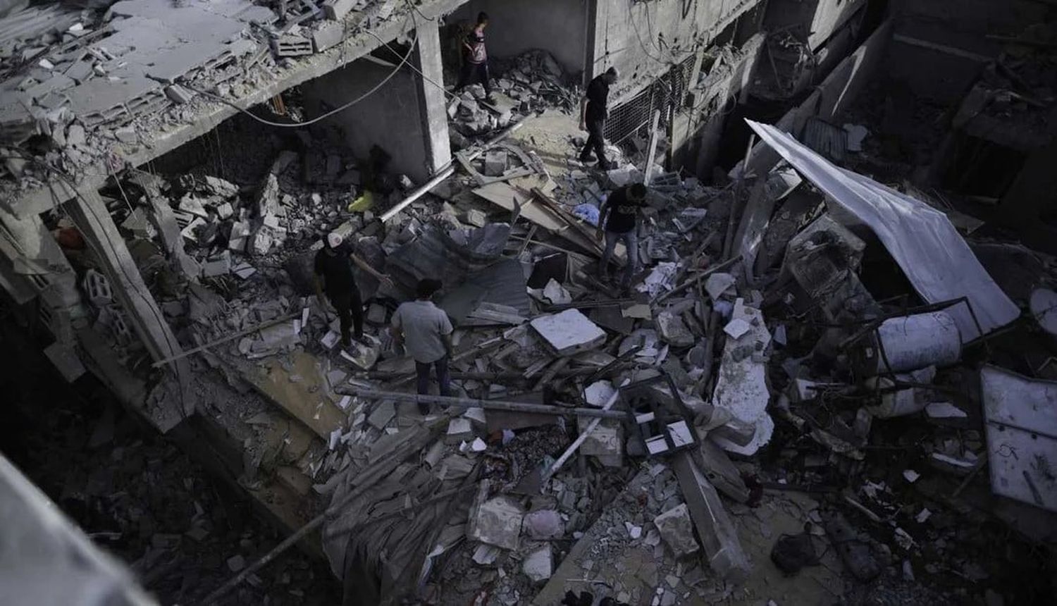 Personas inspeccionan un edificio destruido en el campamento de refugiados de Nuseirat, en el centro de la Franja de Gaza