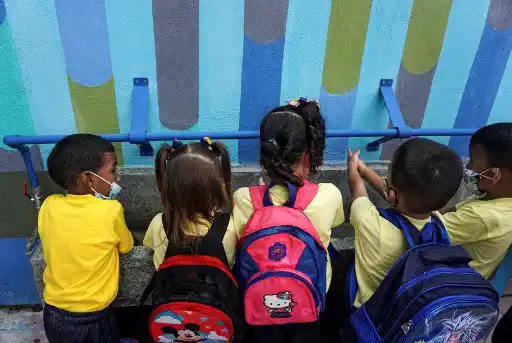 Un grupo de niños se lavan las manos en un grifo múltiple que suministra agua de lluvia filtrada en el preescolar Fermín Toro, beneficiario del programa "Lata de Agua", en el populoso barrio de Petare en Caracas
