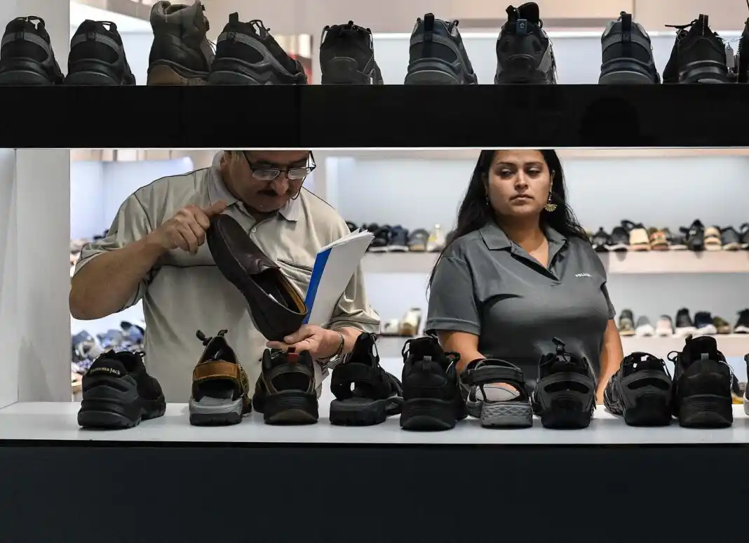Personas observan zapatos en una tienda de calzado.