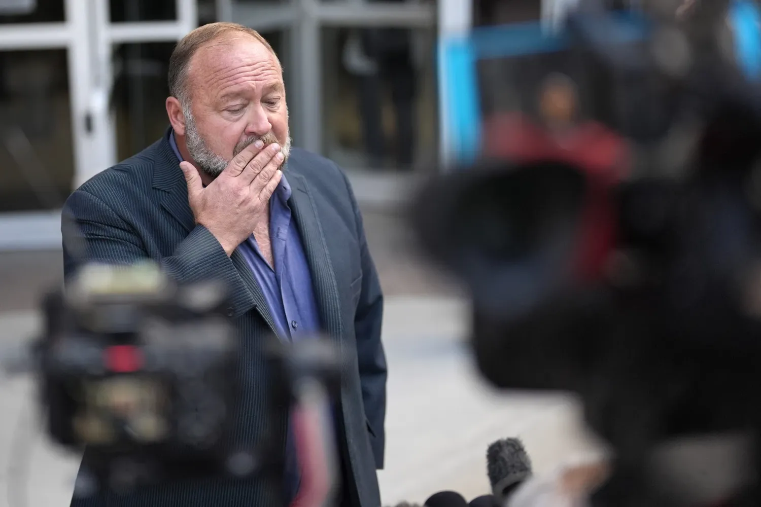 Alex Jones pauses before speaking to the media after arriving at the federal courthouse for a hearing in front of a bankruptcy judge