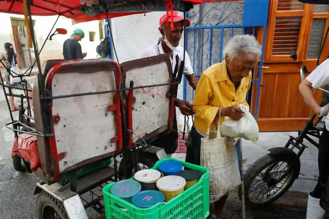 Una mujer lleva una bolsa con recipientes de comida de un comedor social.