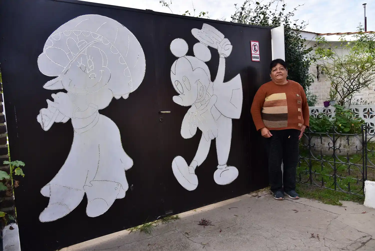 Marcela Ponce frente al portón de su hogar en barrio Cottolengo con las figuras de Minnie y Mickey Mouse.