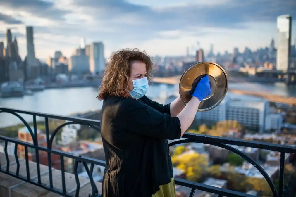Laurie Garrett, periodista ganadora del Premio Pulitzer, echa porras a los trabajadores esenciales desde la azotea de su edificio en Nueva York. (Joshua Bright/The New York Times).