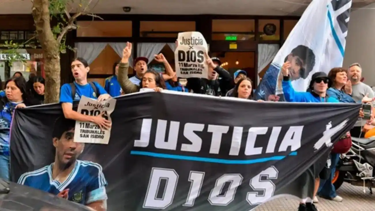 Varias personas aguardan fuera de los tribunales de San Isidro exigiendo justicia por la muerte de Maradona.