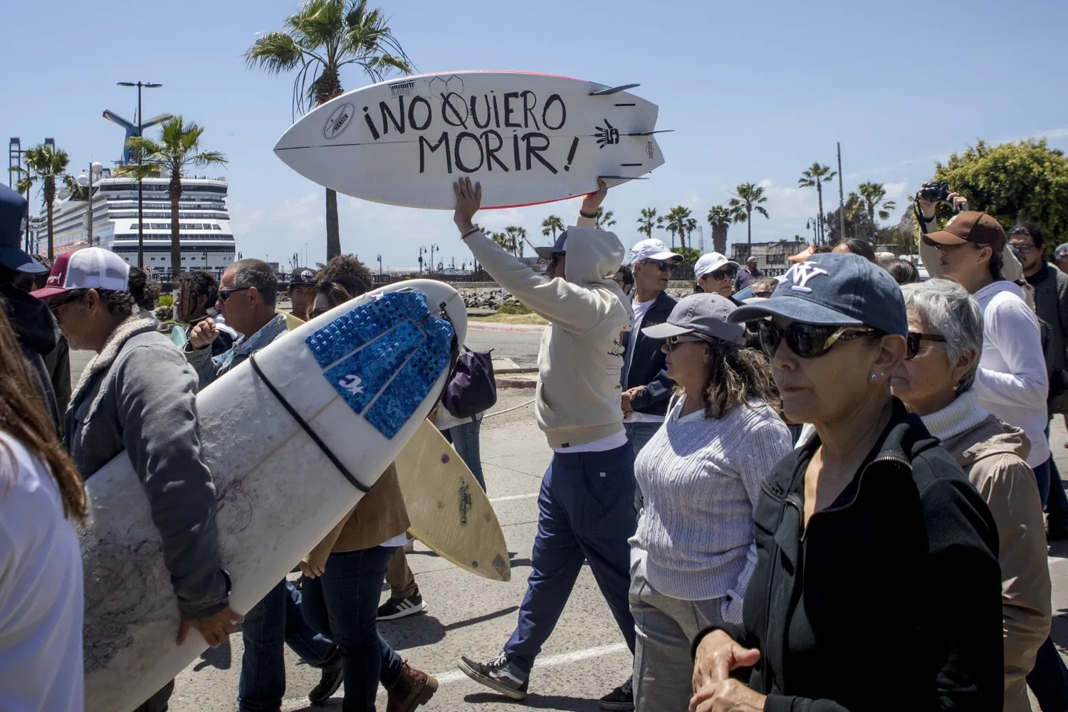 A demonstrator holding a bodyboard written in Spanish "I don't want to die" protests the disappearance of foreign surfers.