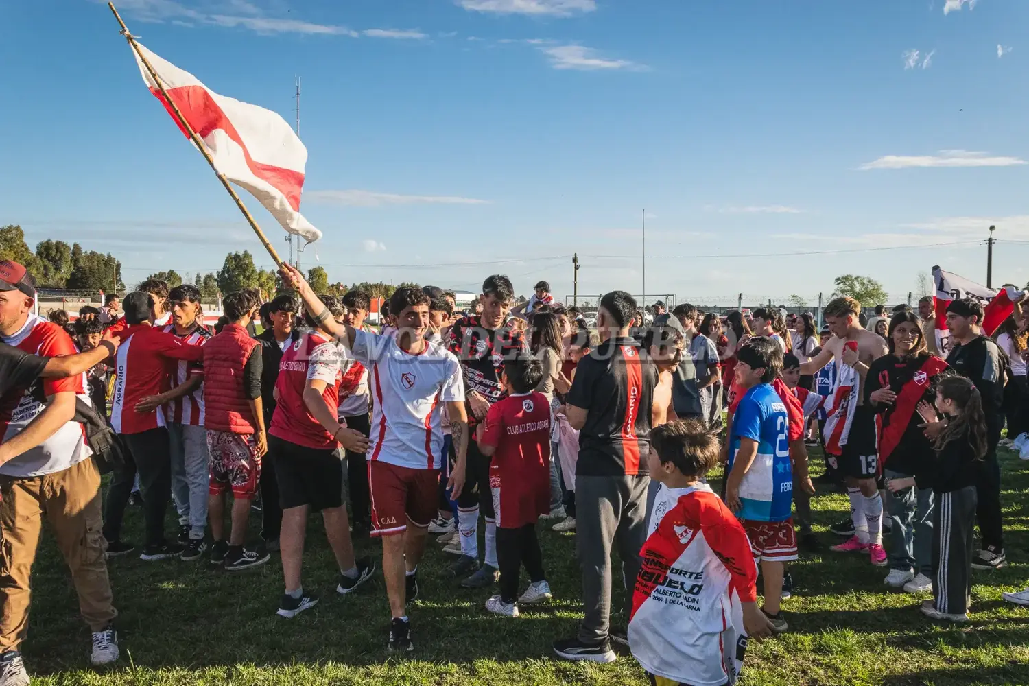 Hinchas y jugadores festejan en el césped del Diego Armando Maradona, la vuelta de Agrario a la Primera División de la Liga Regional Tresarroyense de Fútbol