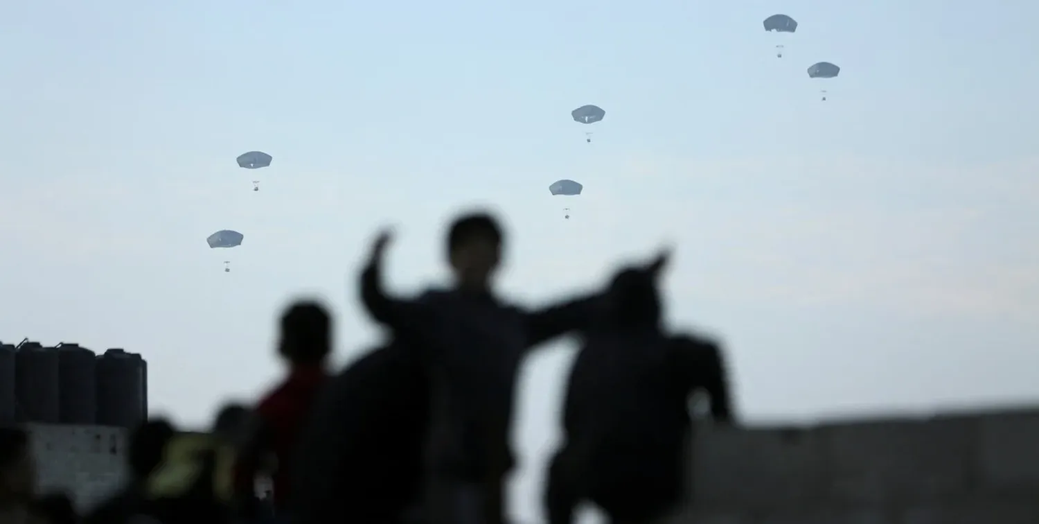 La gente observa cómo el ejército estadounidense lleva a cabo su primera entrega de ayuda sobre Gaza, en medio del conflicto en curso entre Israel y el grupo islamista palestino Hamas. Foto: REUTERS / Kosay Al Nemer.