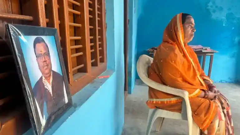 Shashi Verma, cuñada del fallecido trabajador electoral Viay Kumar Verma, se sienta junto a su foto en su casa cerca de Lucknow, Uttar Pradesh, India [Sumaiya Ali/Al Jazeera]