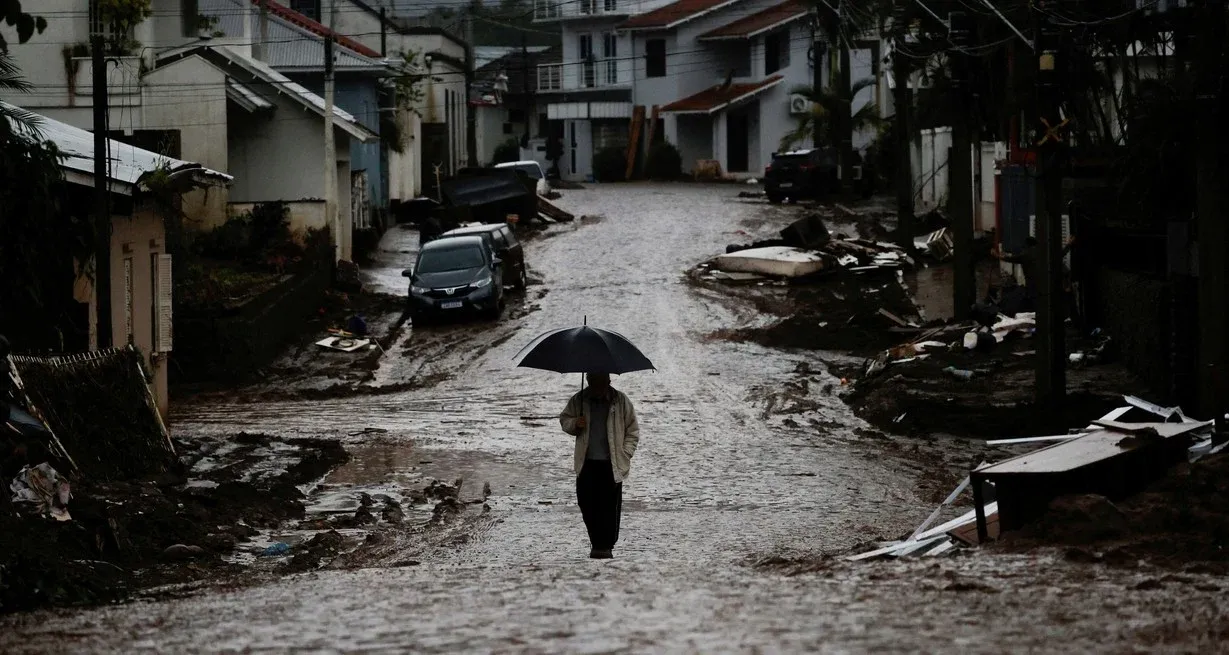 Un hombre con un paraguas camina por una calle parcialmente destruida después de las inundaciones en Mucum, estado de Rio Grande do Sul. Crédito: Reuters/Adriano Machado