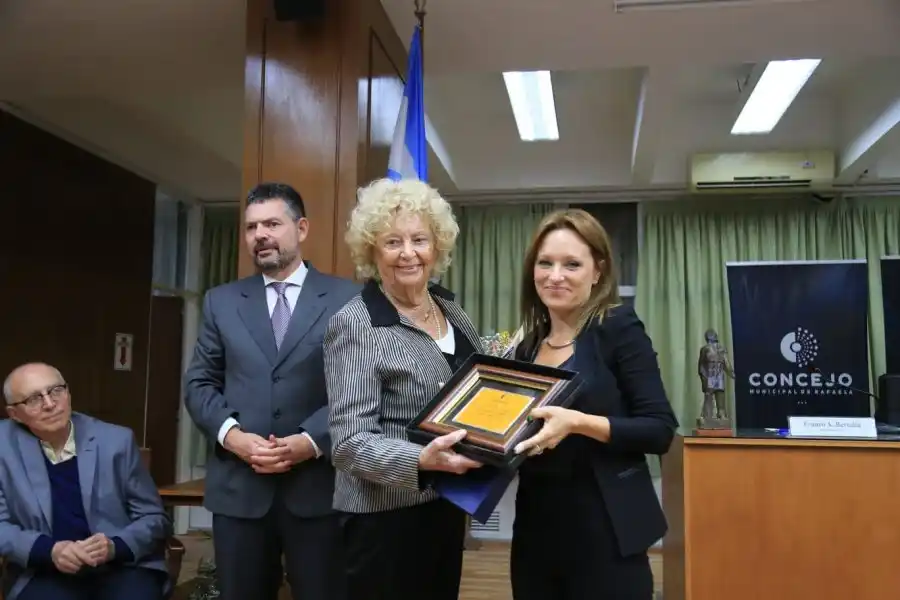 Brenda Vimo, autora del proyecto que distingue a Toti Tieri le entrega la plaqueta recordatoria