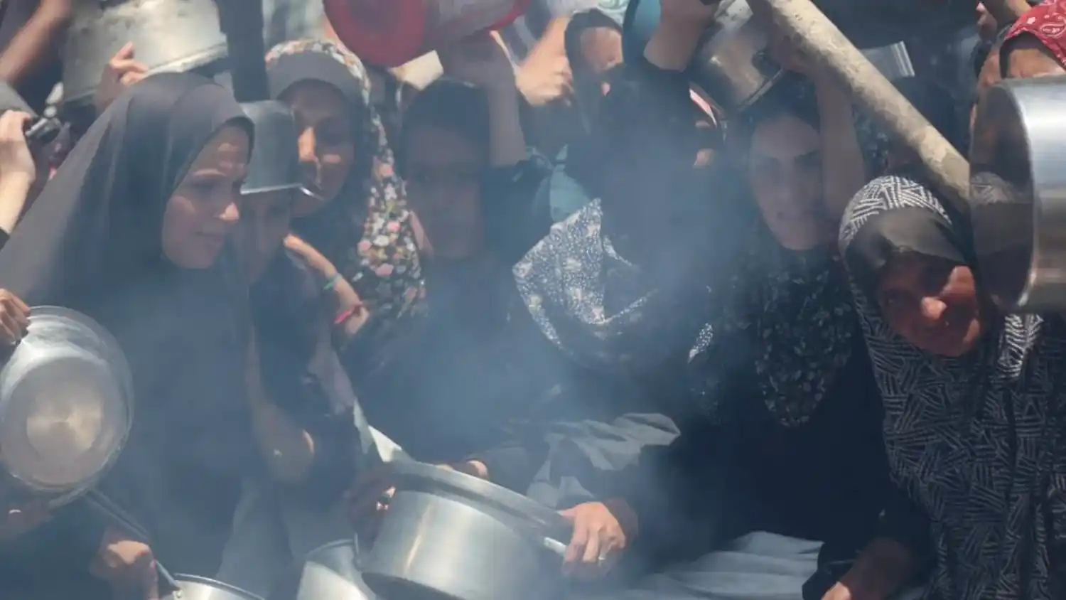 Mujeres palestinas alzan ollas vacías en Gaza, en un intento desesperado por conseguir alimentos en medio del bloqueo y la escasez humanitaria.