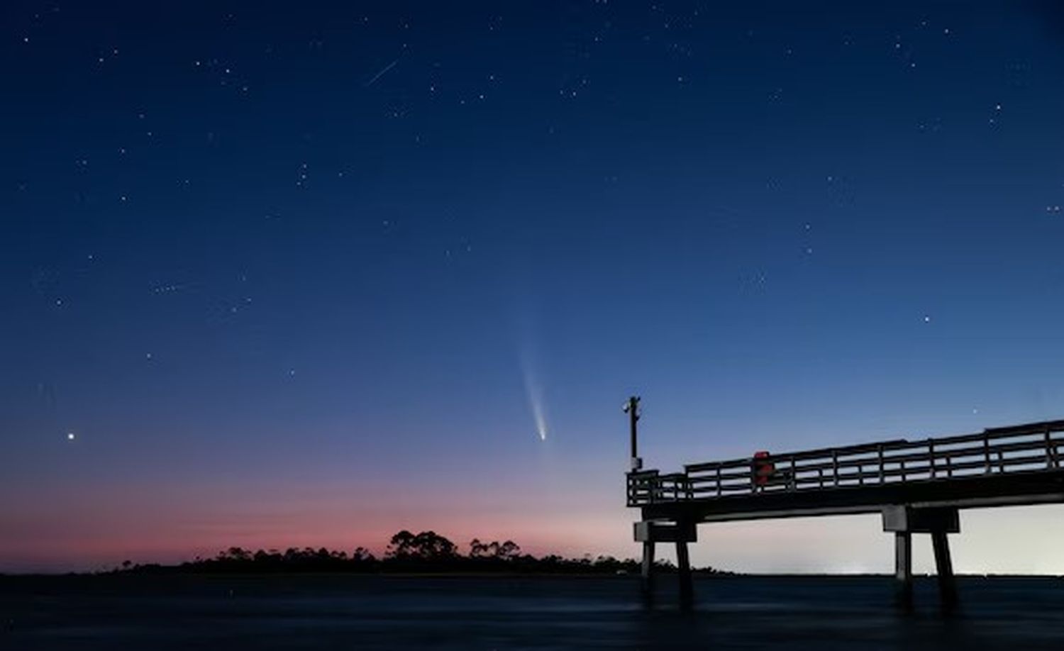 Apenas después de la puesta del Sol, el cometa es visible en el muelle de pescadores de Walk Pier de isla Tybee Island en Georgia, Estados Unidos