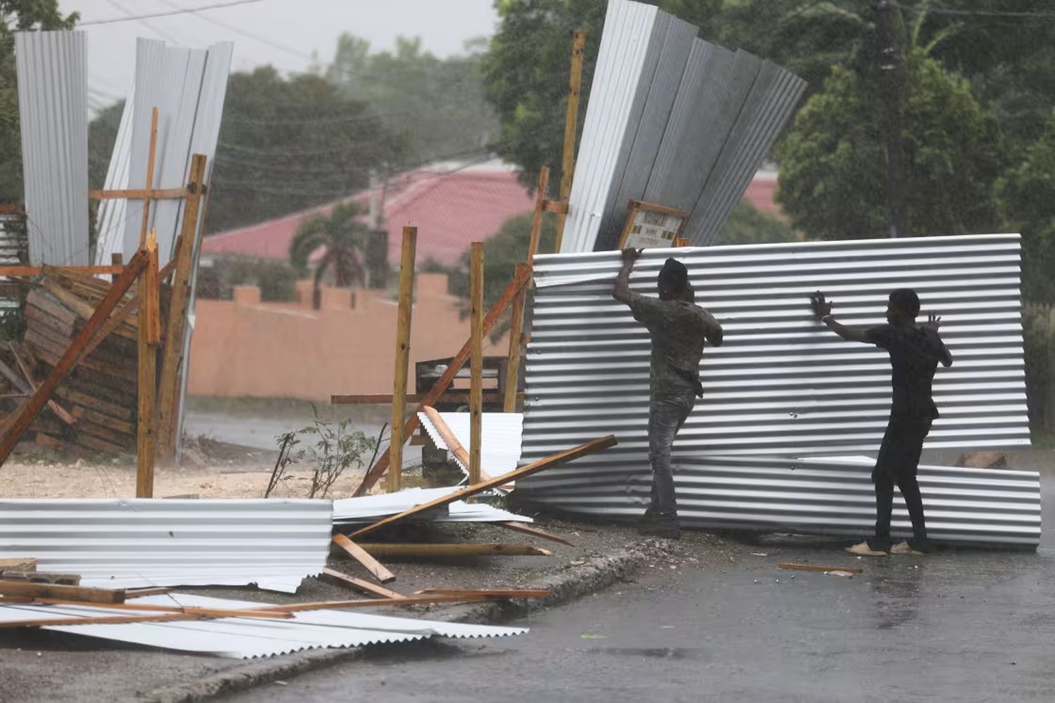 Workers save pieces of a tin fence that was blown apart as Hurricane Beryl passed through Kingston, Jamaica, on Wednesday