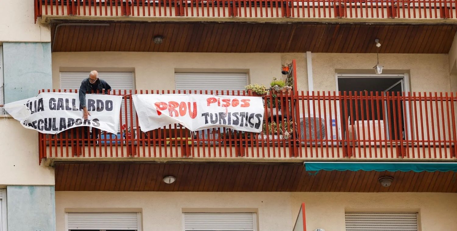 Un residente cuelga una bandera en contra del alquiler temporario en Barcelona.