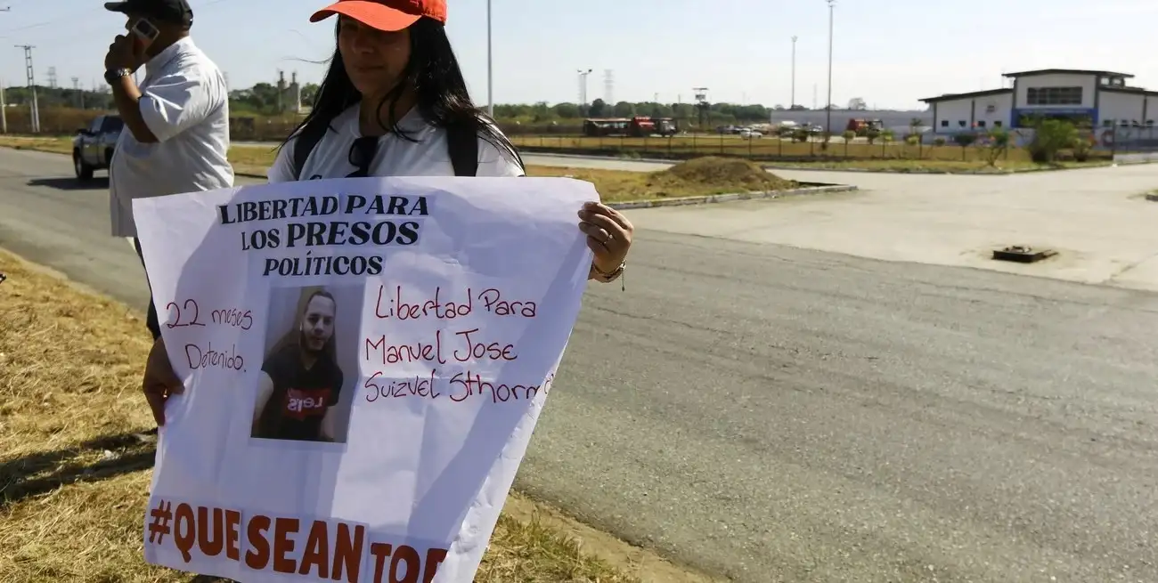 Una mujer sostiene una pancarta de un preso político en Venezuela. Foto: REUTERS / Juan Carlos Hernandez.