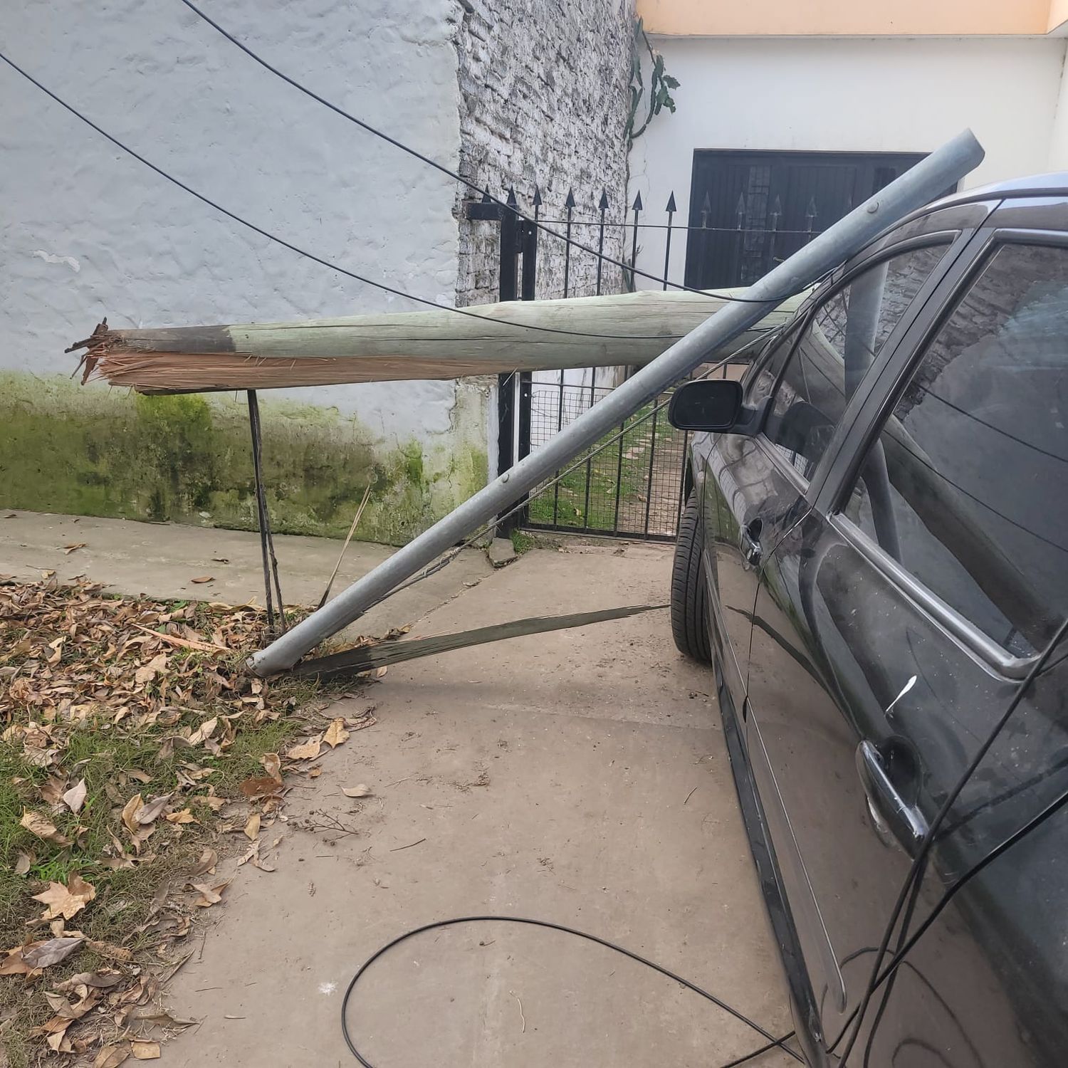 Así cayó uno de los postes sobre un auto estacionado sobre la vereda tras el paso del camión que arrastró los cables.