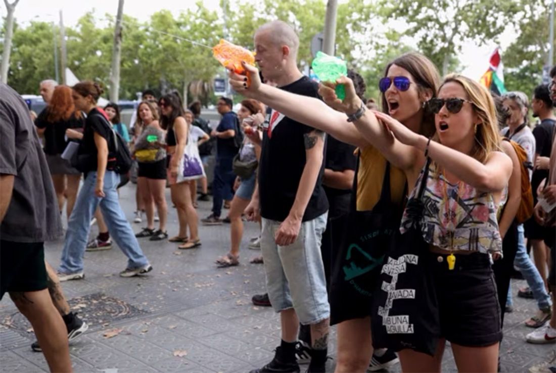 Manifestantes disparan agua con pistolas de agua a los turistas durante una protesta contra el turismo de masas en Barcelona, ​​España.