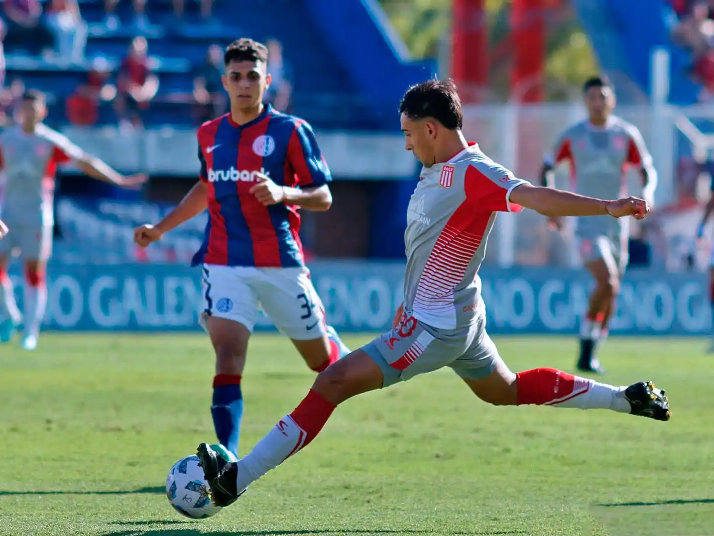 Meza intenta el pase largo, seguido de cerca por Medina.