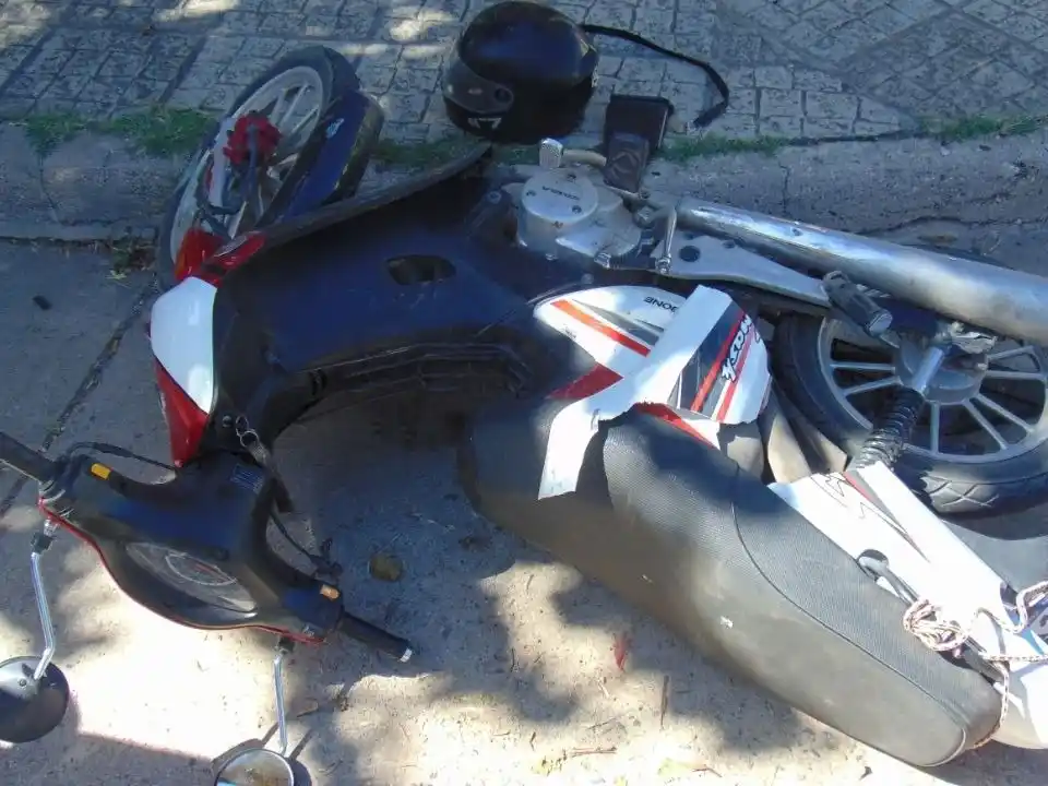 La moto tendida en el piso tras la colisión.