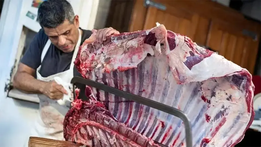 Un carnicero corta carne en un mercado