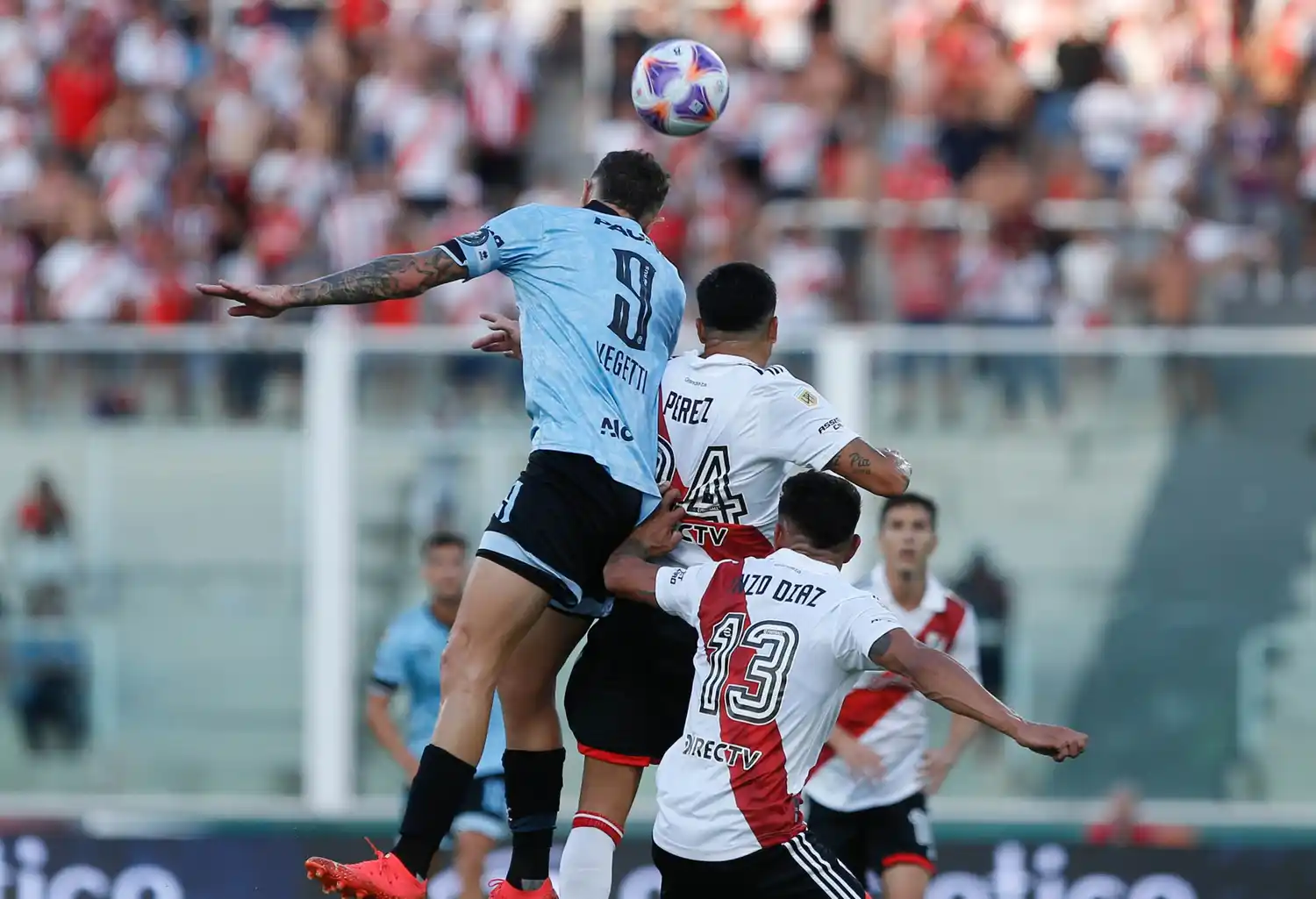 Vegetti gana arriba ante Enzo Pérez, con Enzo Díaz cerca. El atacante fue autor de los dos goles de Belgrano.
