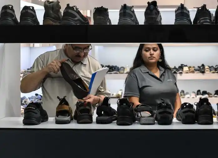 Personas observan zapatos en una tienda de calzado.