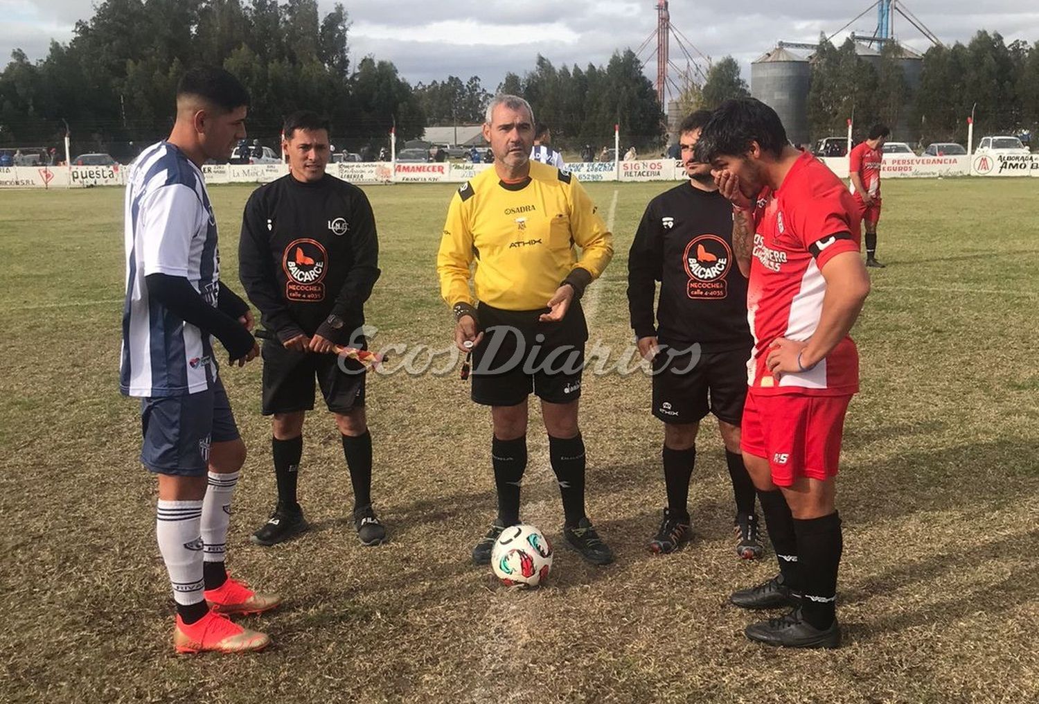 Sorteo entre capitanes y árbitros en el círculo de la mitad de la cancha