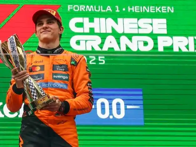 Oscar Piastri celebrando en lo más alto del podio del GP de China, con el trofeo en alto, vestido con el buzo de McLaren.