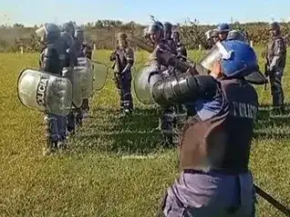Efectivos de la Guardia de Infantería de la Policía de Formosa realizan ejercicios de entrenamiento táctico y formación profesional en un campo abierto, utilizando escudos y equipo de protección reglamentario para sus tareas de seguridad pública.