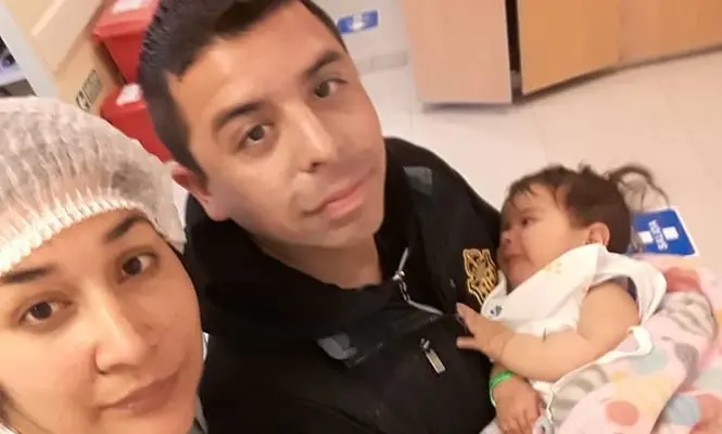 Milena en brazos de sus papás, antes de la operación.