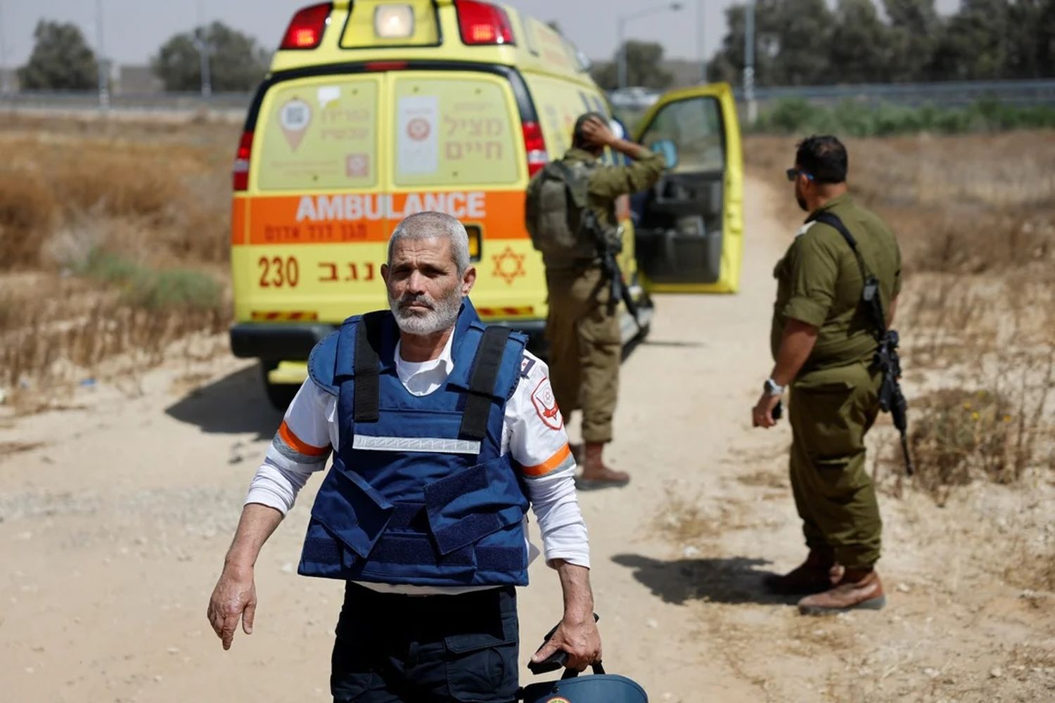 Un médico camina junto a varios soldados israelíes cerca de una ambulancia después de un ataque mortal.
