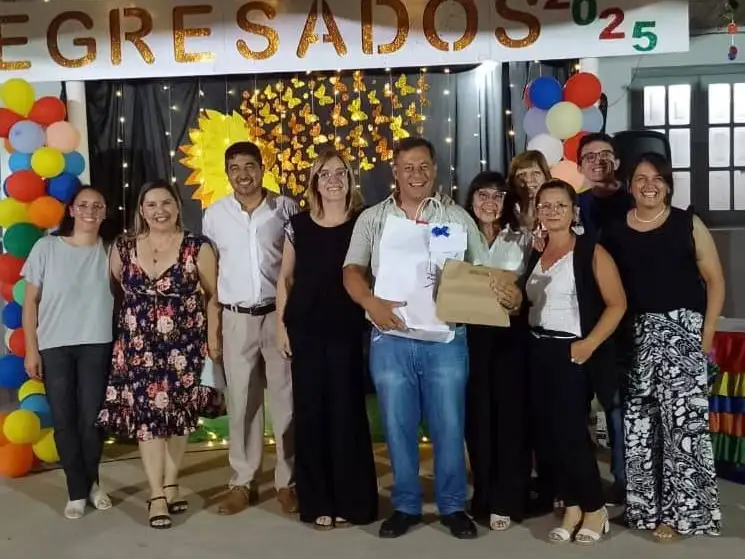 Toda la emoción del homenajeado, sosteniendo un obsequio junto a ex compañeros y colegas de otras escuelas.