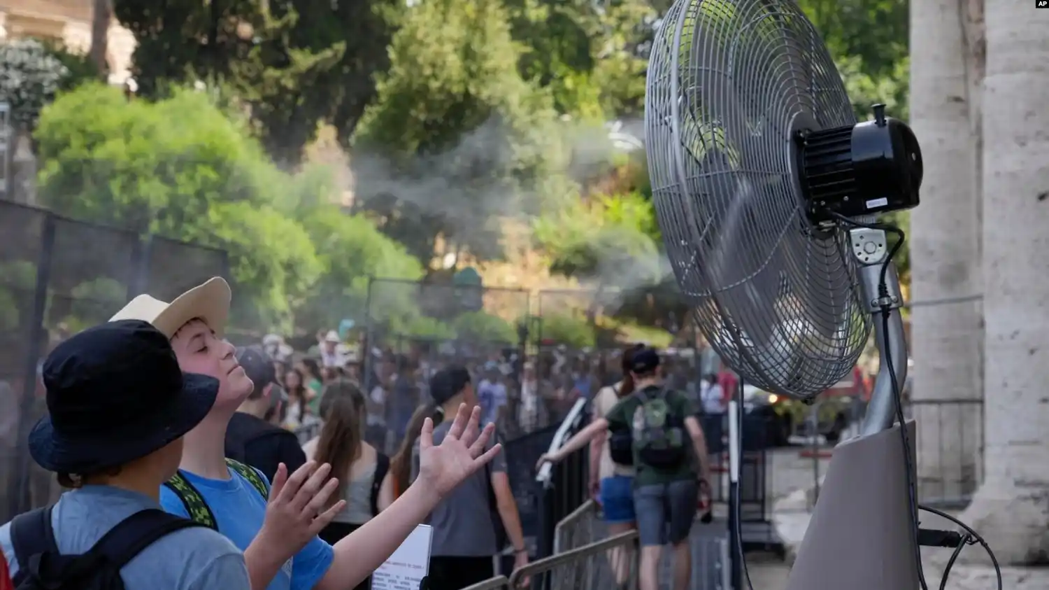 Turistas se refrescan frente a un ventilador eléctrico en la entrada del Coliseo de Roma el 18 de julio de 2023